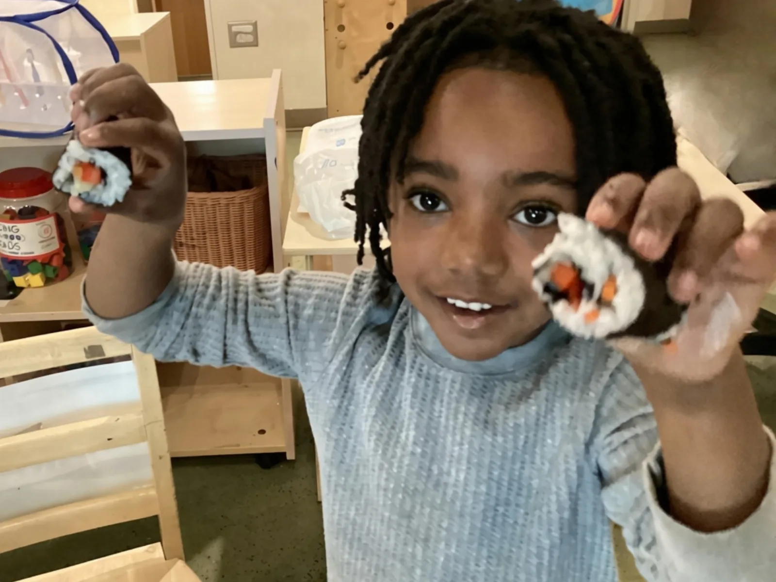 A child proudly shows the sushi she made